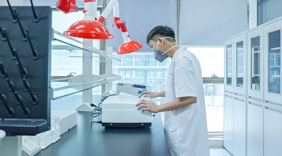 A Fenda laboratory technician operating a testing instrument at a lab bench.